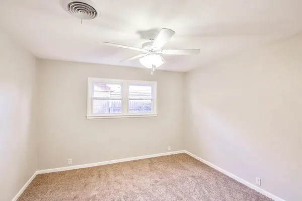an empty room with windows and fan