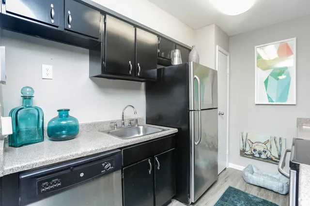 a kitchen with stainless steel appliances a sink a refrigerator and a counter top space