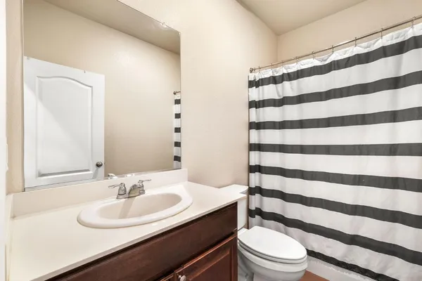 a bathroom with a sink a toilet a mirror and shower curtain