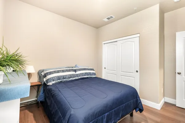 a bedroom with a bed and a potted plant on the dresser