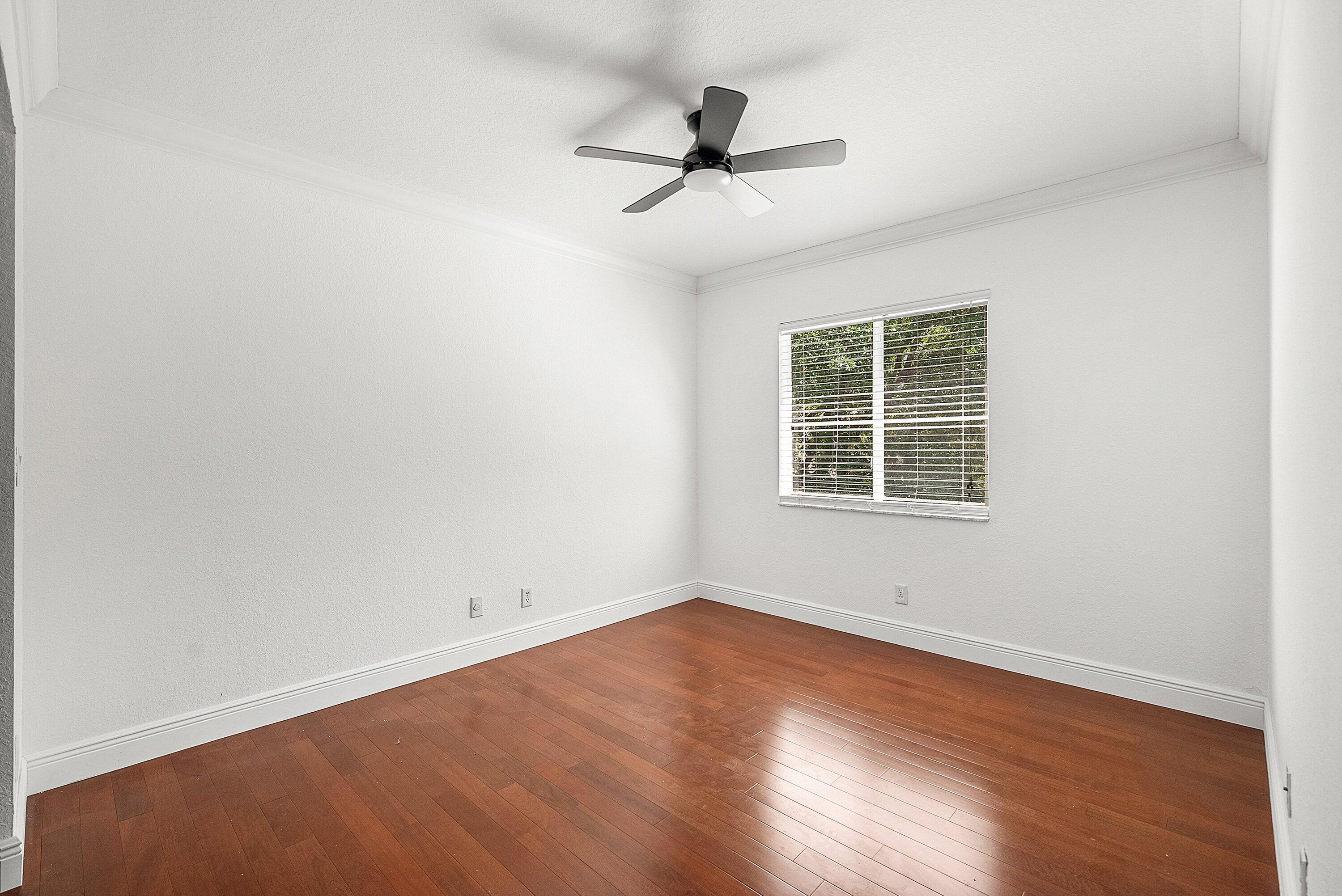 1509 Sage Wood Court Riviera Beach, FL 33404 - Photo 26 of 59 an empty room with wooden floor ceiling fan and windows