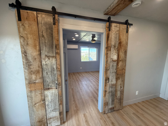 14183 High Mesa Loop Duchesne, UT 84021 - Photo 51 of 56 Hall featuring a barn door, light wood-type flooring, and beamed ceiling