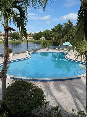 a view of a swimming pool with a yard and palm trees