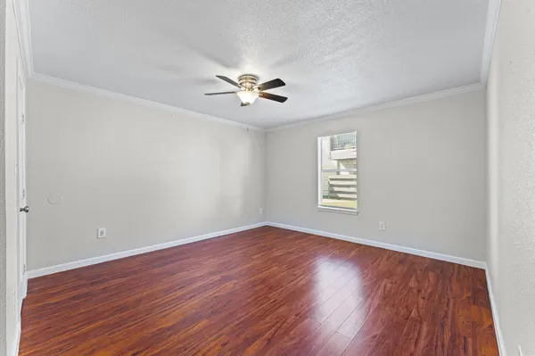 an empty room with wooden floor chandelier fan and windows