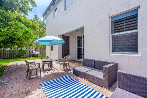 11850 Southwest 250th Terrace Homestead, FL 33032 - Photo 14 of 47 a patio with patio a table and chairs under an umbrella with wooden fence