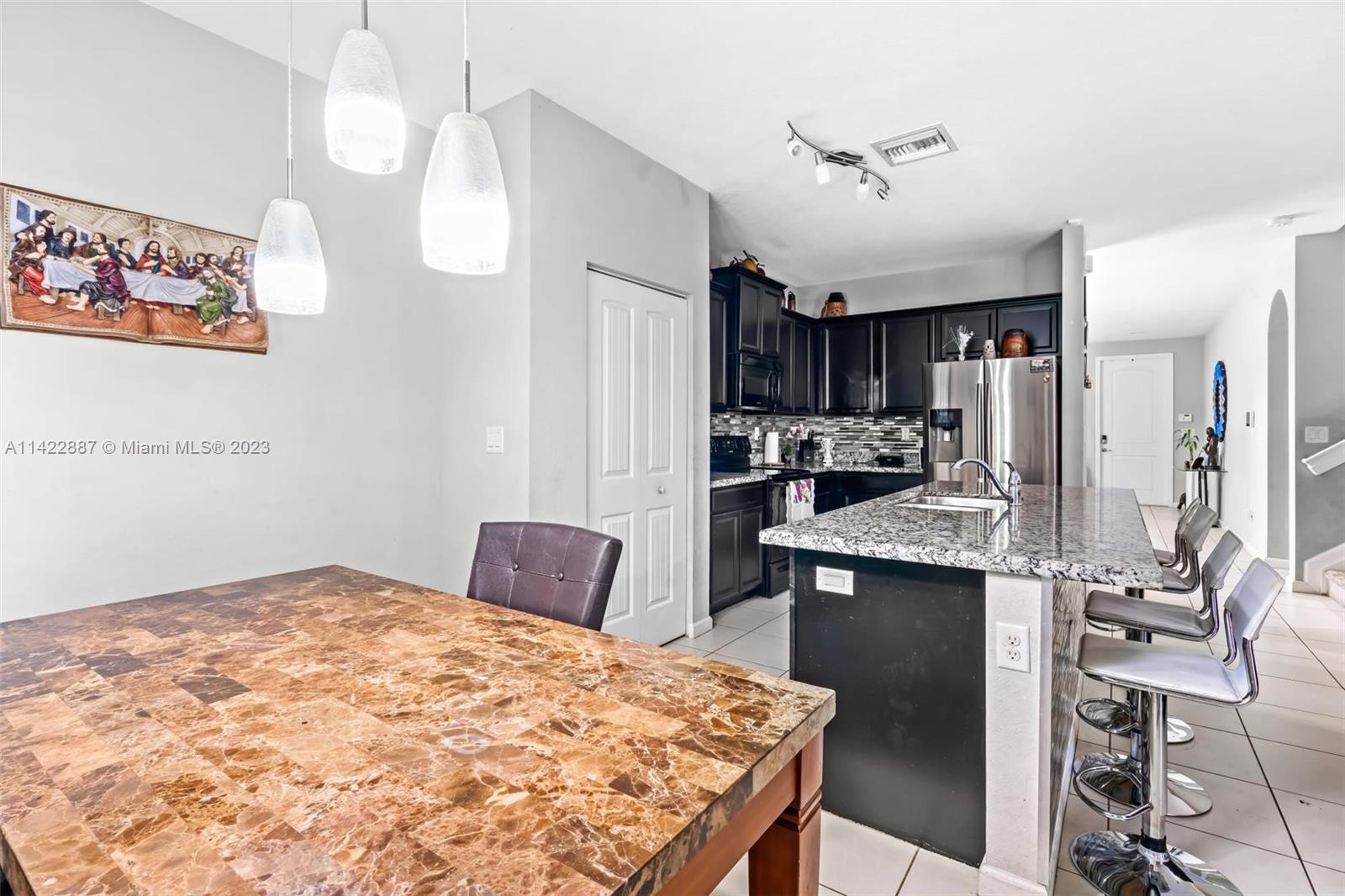 11850 Southwest 250th Terrace Homestead, FL 33032 - Photo 22 of 47 a kitchen with kitchen island a stove a refrigerator a sink a dining table and chairs with wooden floor