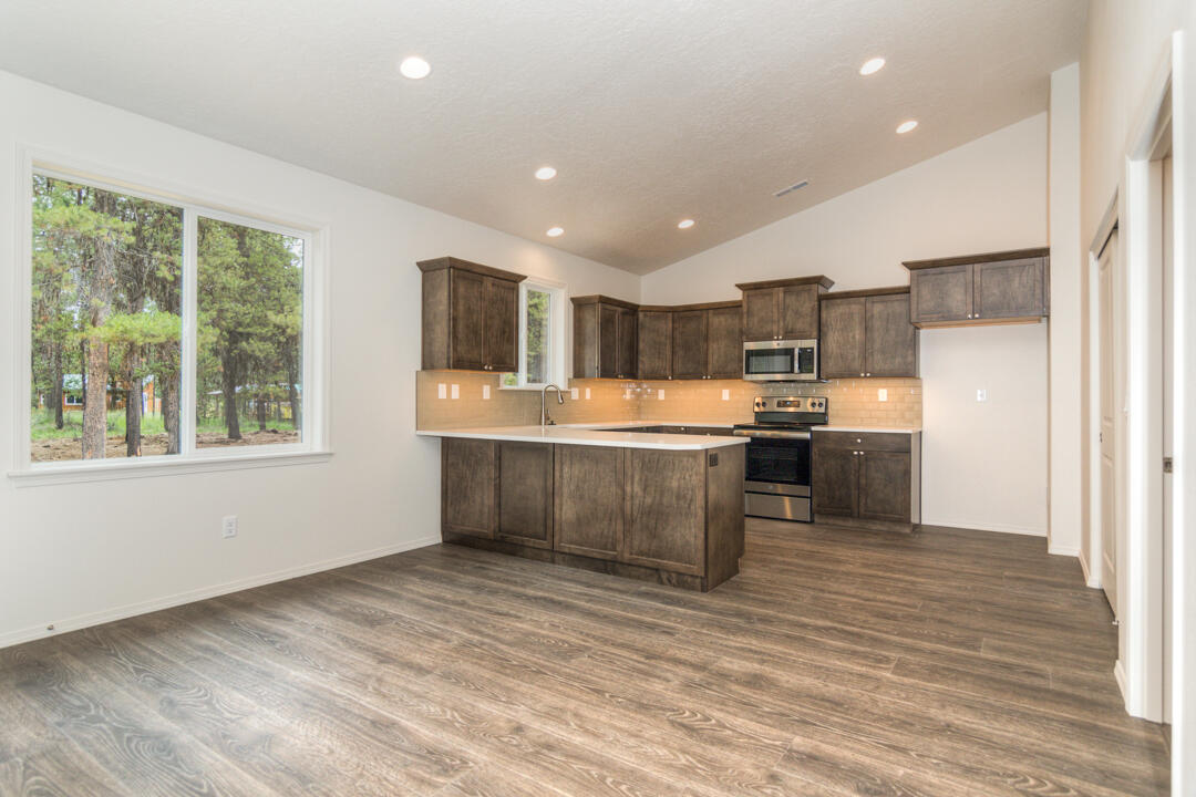 17084 Indio Road Bend, OR 97707 - Photo 10 of 40 a kitchen with stainless steel appliances kitchen island granite countertop a sink counter space cabinets and a large window