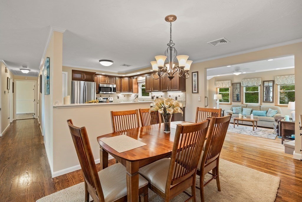 27 Phyllis Road Raynham, MA 02767 - Photo 8 of 42 a view of a dining room and livingroom with furniture wooden floor a chandelier