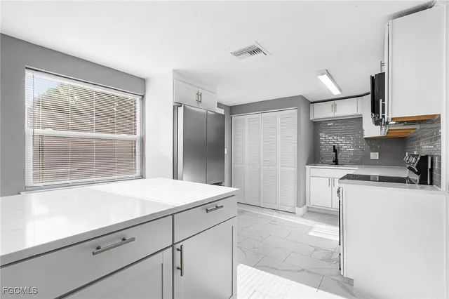 a kitchen with stainless steel appliances kitchen island granite countertop a refrigerator and a sink