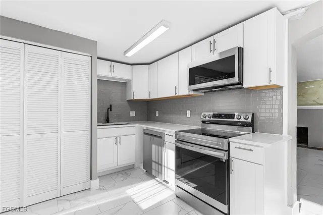 a kitchen with stainless steel appliances a stove microwave and sink