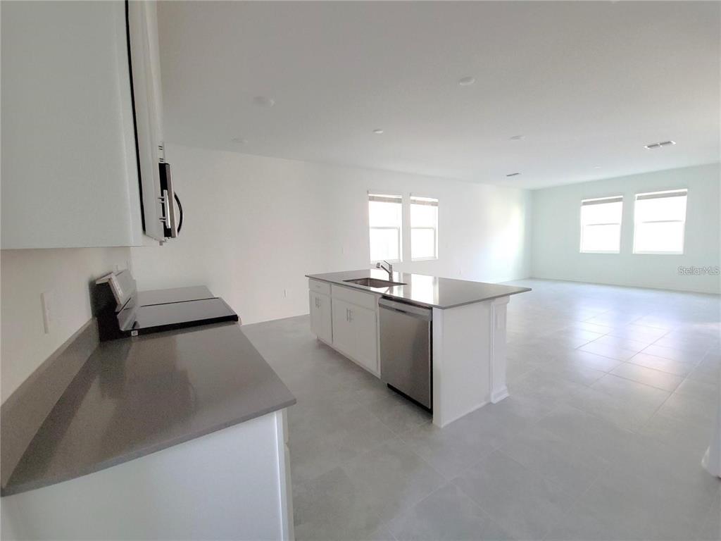 6182 Shavasana Road Clermont, FL 34714 - Photo 11 of 30 a kitchen with stainless steel appliances a sink a stove and white cabinets