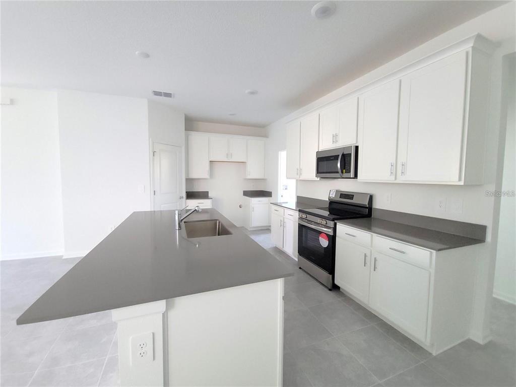6182 Shavasana Road Clermont, FL 34714 - Photo 7 of 30 a kitchen with granite countertop a sink a stove top oven a counter top space and cabinets