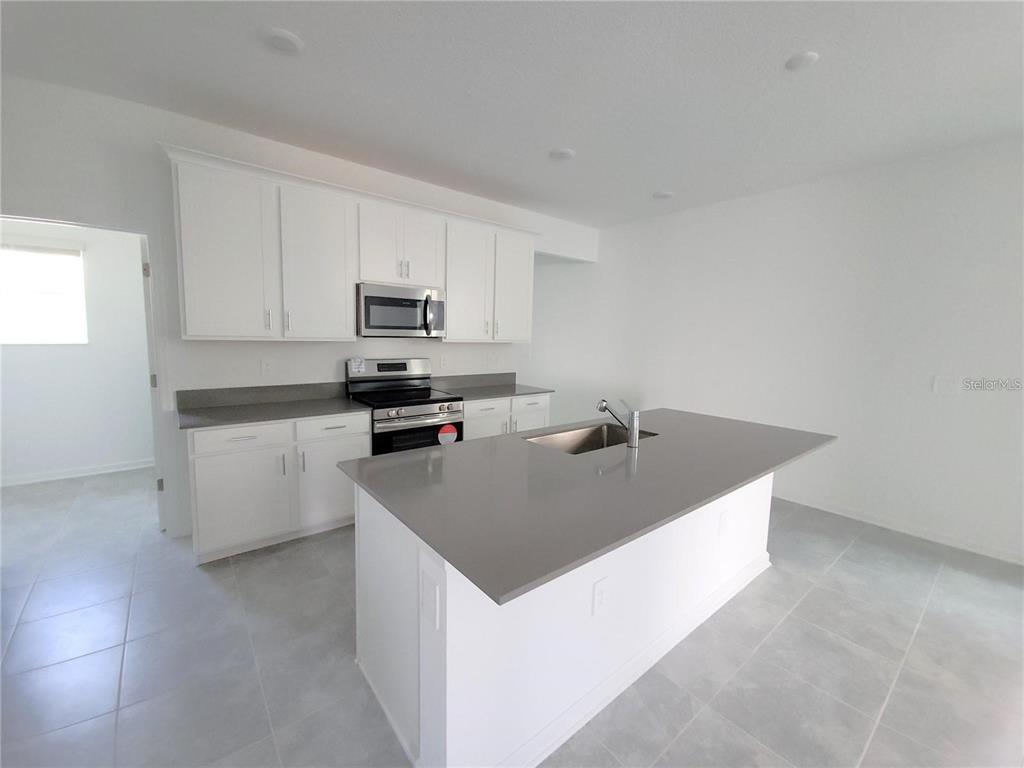 6182 Shavasana Road Clermont, FL 34714 - Photo 10 of 30 a kitchen with stainless steel appliances a sink a stove top oven a counter space and cabinets