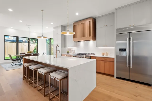 a kitchen with stainless steel appliances granite countertop a sink a stove a refrigerator and island with wooden floor