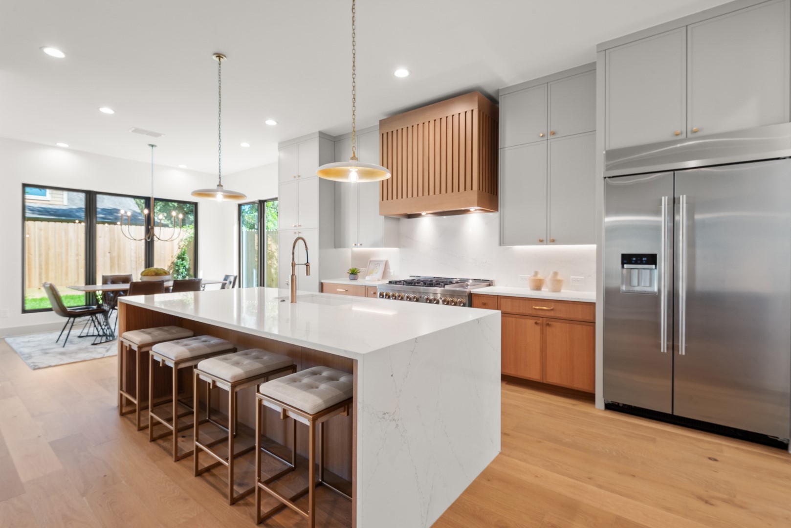 a kitchen with stainless steel appliances granite countertop a sink a stove a refrigerator and island with wooden floor