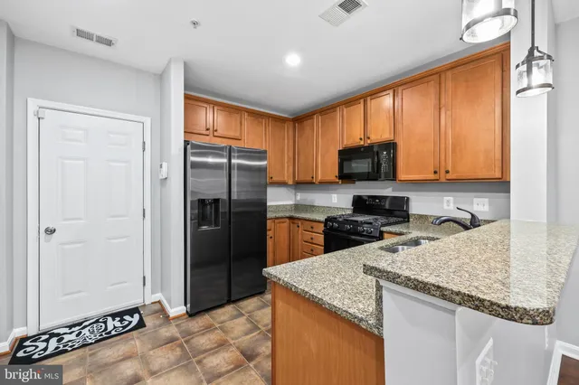 a kitchen with granite countertop wooden cabinets a refrigerator and a sink
