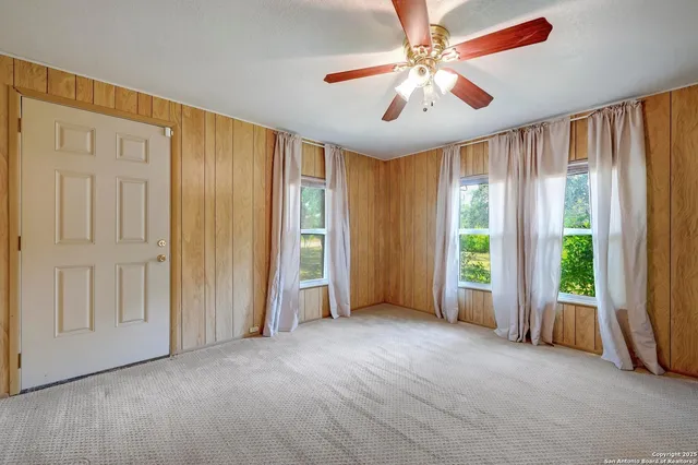 an empty room with windows and fan