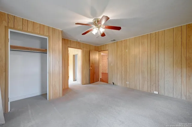 a view of an empty room and chandelier fan