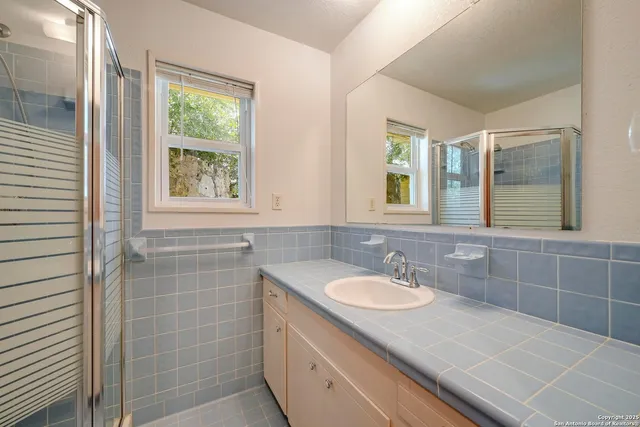 a bathroom with a granite countertop sink a toilet a mirror and window