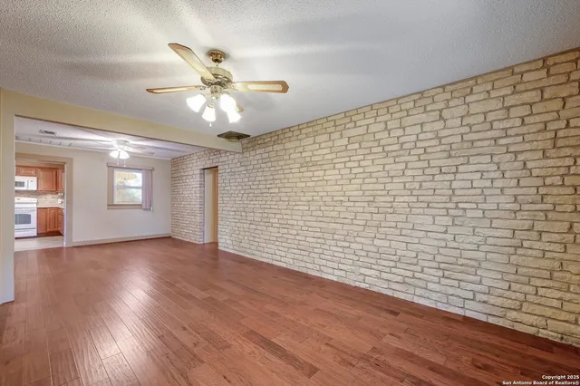 a view of an empty room with window and wooden floor