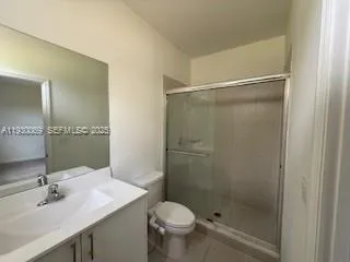 a bathroom with a shower sink vanity mirror and toilet