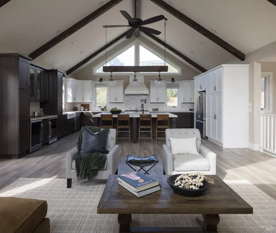 a living room with stainless steel appliances furniture a rug and a kitchen view