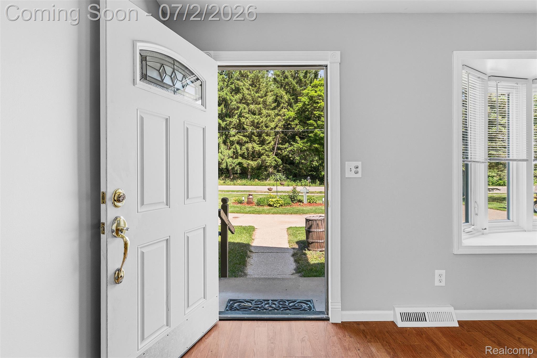 305 East Road Holly, MI 48442 - Photo 5 of 41 Entryway featuring a white paneled door with decorative glass insert and brass hardware, complemented by a bay window with white blinds and wood-finish flooring