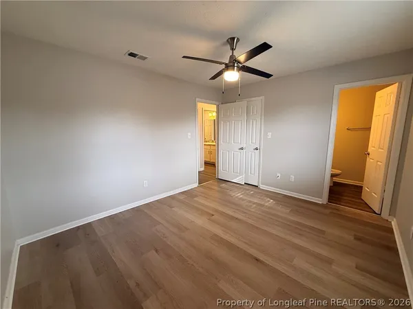 an empty room with wooden floor fan and windows