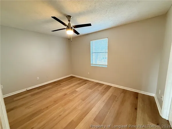 an empty room with a window and ceiling fan