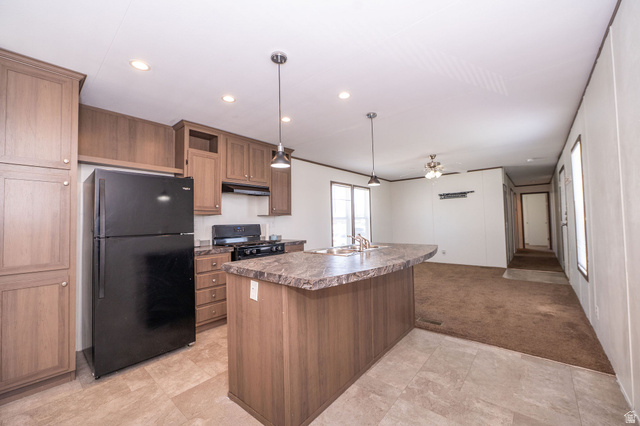2491 Highway 89, Unit 403 Pleasant View, UT 84404 - Photo 13 of 32 Kitchen featuring wood-finish cabinetry, black appliances, a gas range, and a large island with an integrated sink and pendant lighting