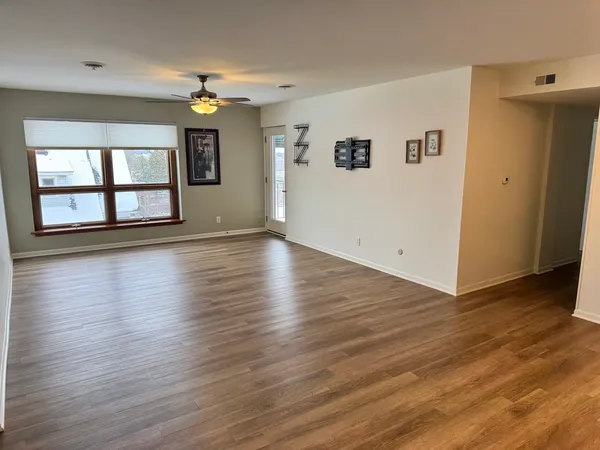 an empty room with wooden floor and windows