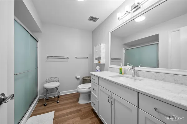 a bathroom with a granite countertop toilet a sink and a mirror