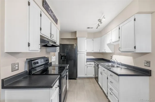 a kitchen with granite countertop a sink stainless steel appliances and white cabinets