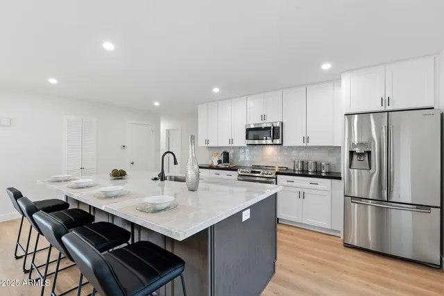 a kitchen with stainless steel appliances granite countertop a sink a stove a microwave and a refrigerator