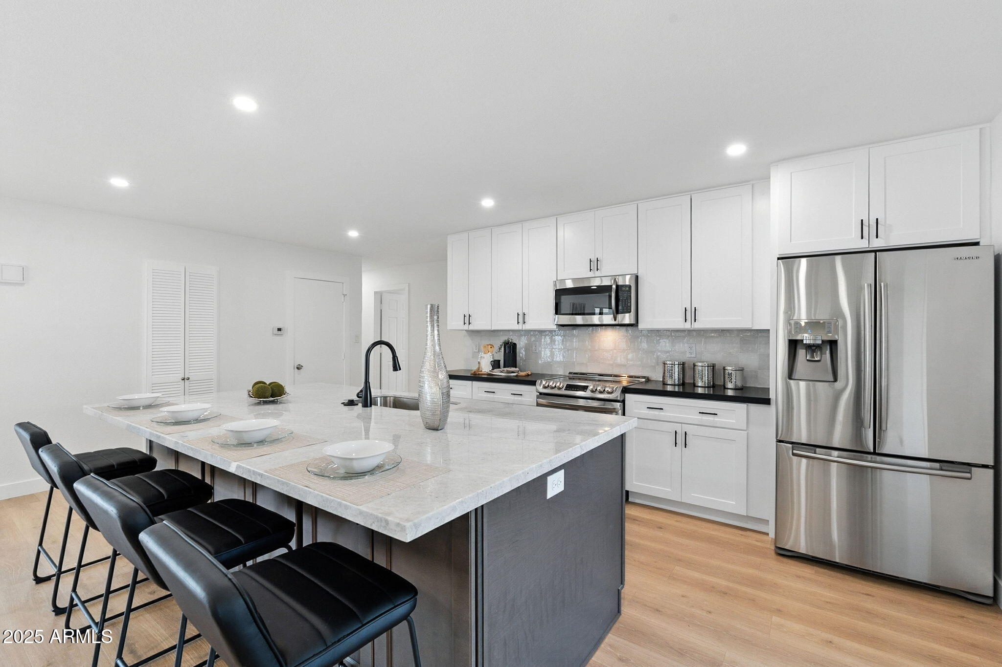 7637 North 7th Avenue Phoenix, AZ 85021 - Photo 21 of 57 a kitchen with stainless steel appliances a stove a sink a refrigerator white cabinets and a table