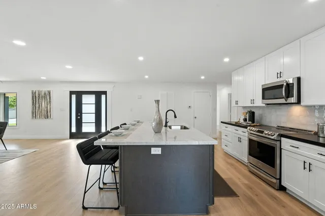a kitchen with stainless steel appliances granite countertop a sink stove and cabinets