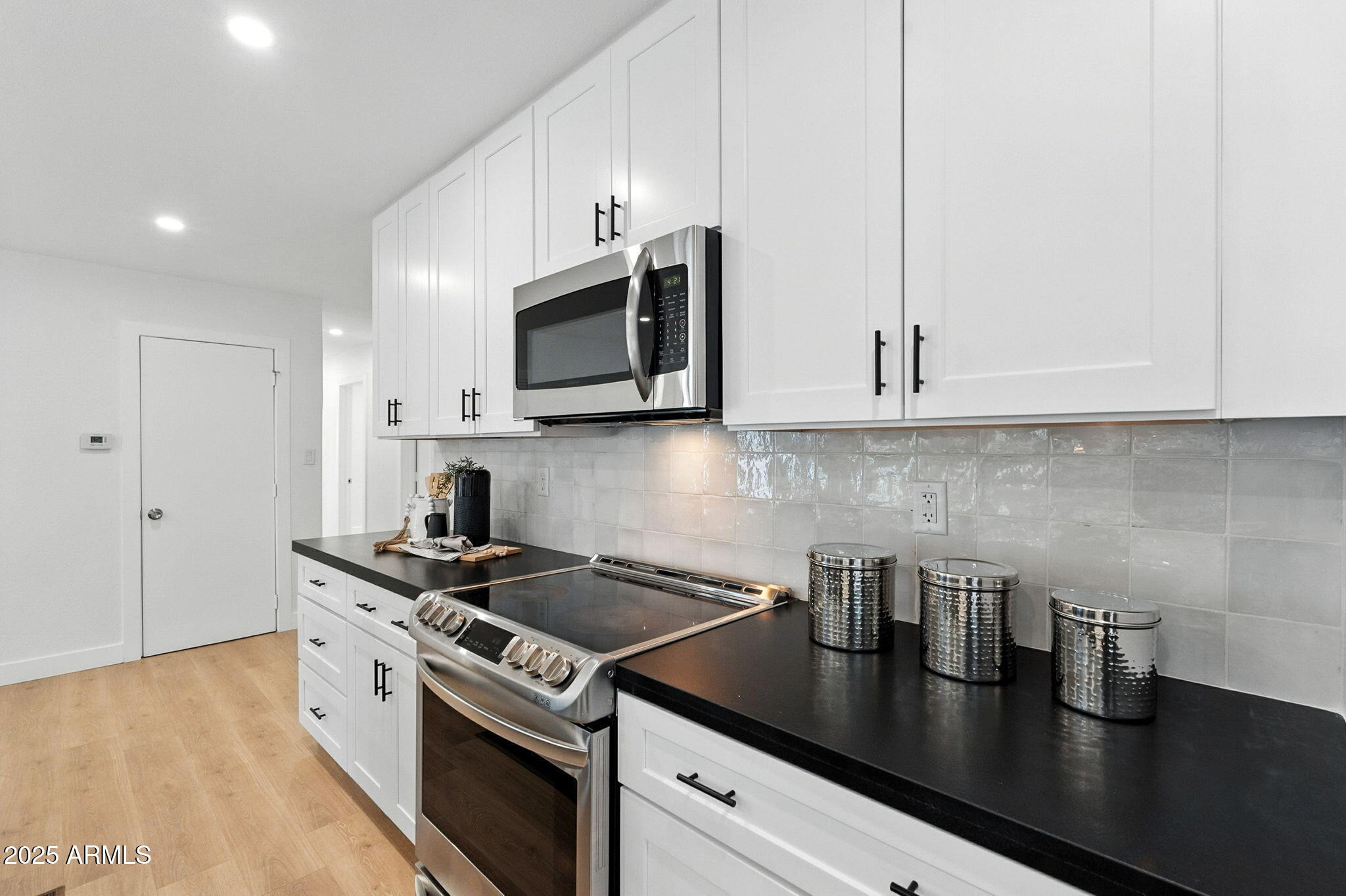 7637 North 7th Avenue Phoenix, AZ 85021 - Photo 25 of 57 a kitchen with stainless steel appliances granite countertop a sink a stove and microwave with wooden floor