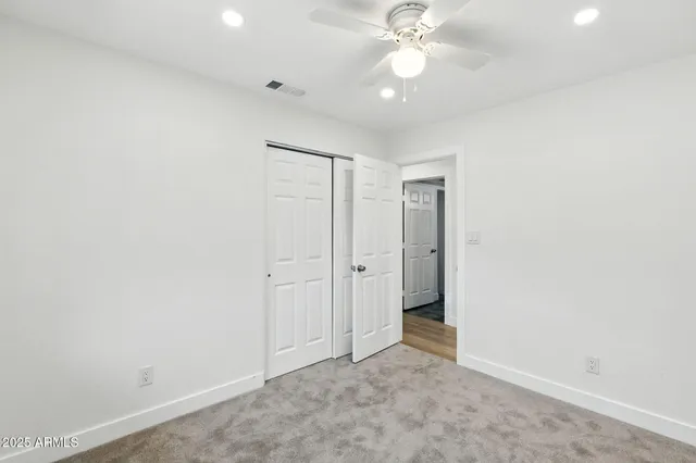 an empty room with a window and a fan