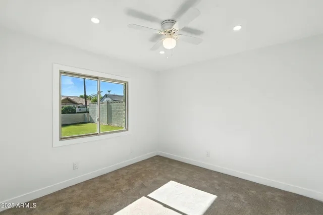 an empty room with a window and a ceiling fan