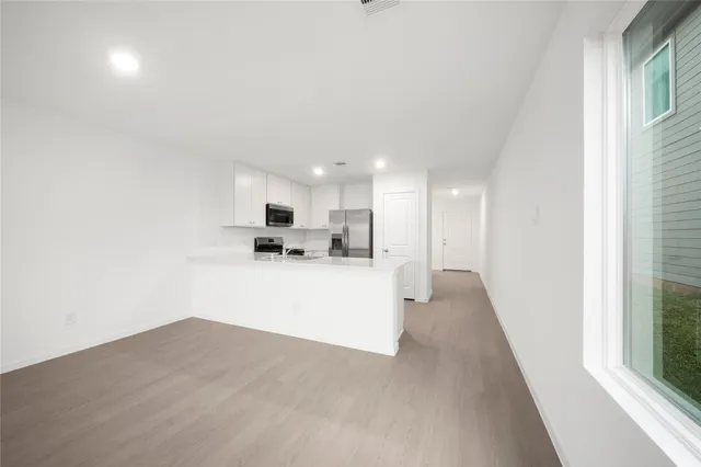 a view of kitchen with kitchen island a sink wooden floor and a refrigerator