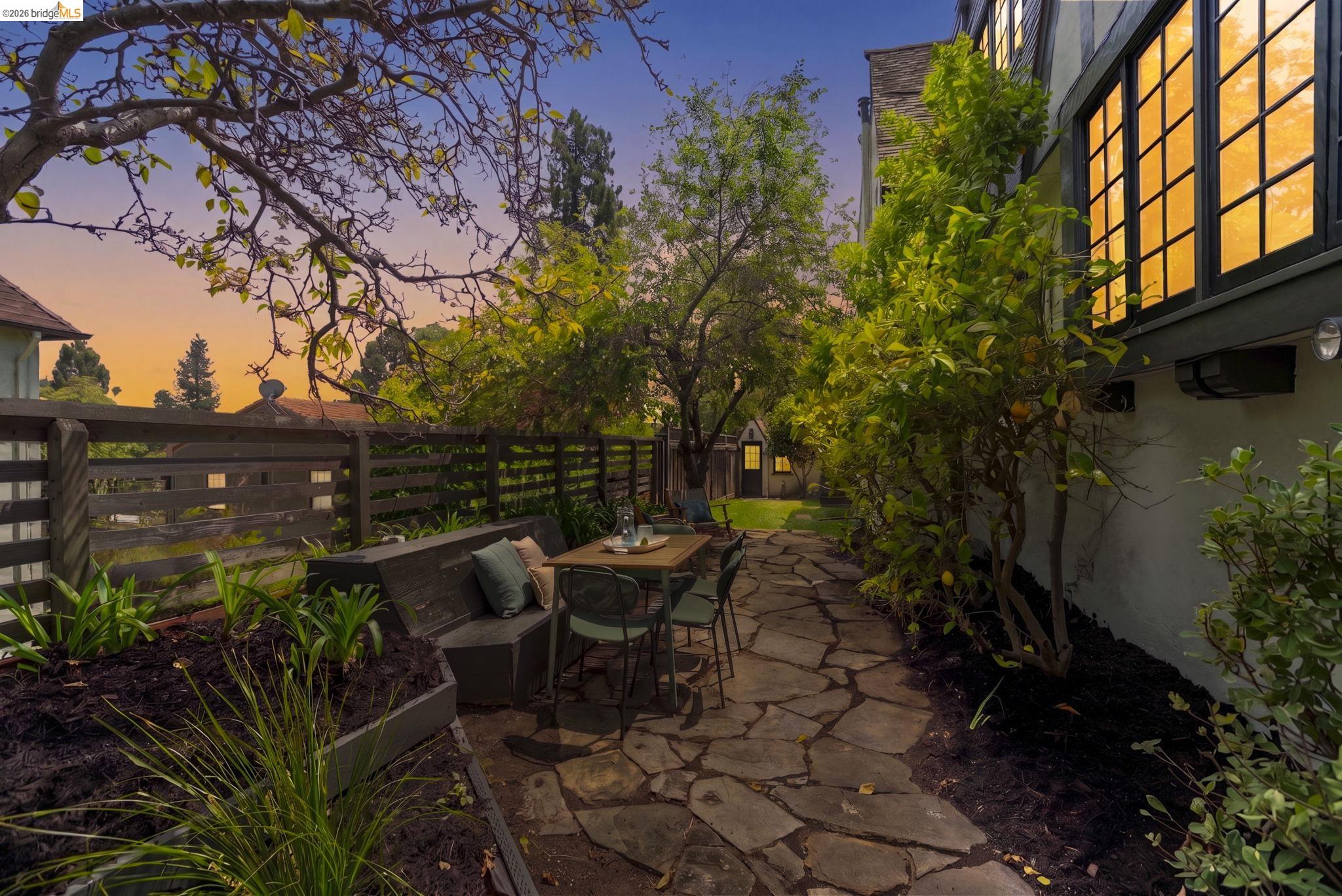 1087 Hubert Road Oakland, CA 94610 - Photo 36 of 67 Stone patio featuring a built-in bench, surrounding mature landscaping, and a fenced perimeter