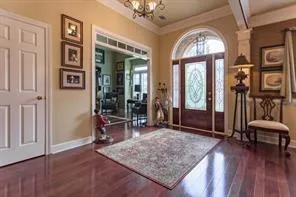 an entryway with a chandelier and wooden floor