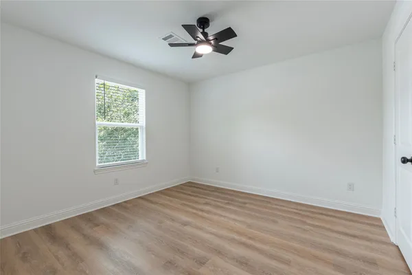 a view of empty room with wooden floor and ceiling fan