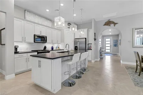 a kitchen that has a lot of white cabinets and stainless steel appliances