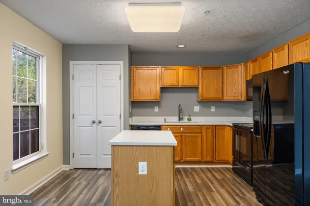 a kitchen with stainless steel appliances granite countertop a refrigerator a sink dishwasher a stove with wooden cabinets and floor