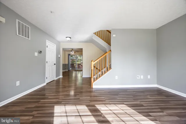 a view of a hallway with wooden floor and a living room