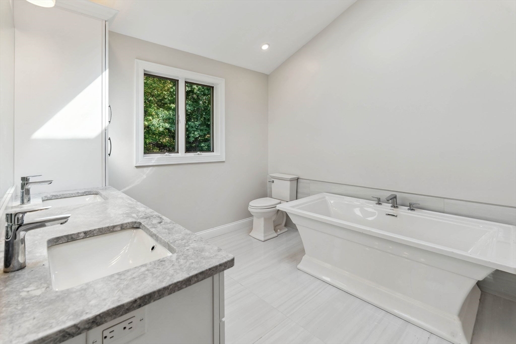 18 Pheasant Street Topsfield, MA 01983 - Photo 25 of 42 a bathroom with a granite countertop sink a large mirror and a bathtub