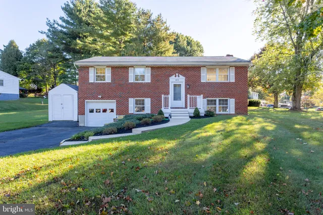 a front view of house with yard and trees in the background