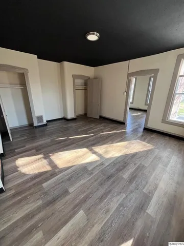 a view of an empty room with wooden floor and closet