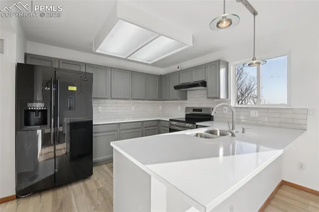 a kitchen that has a sink a refrigerator and cabinets